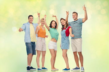 Obraz premium friendship and people concept - group of happy smiling friends over festive lights on green background