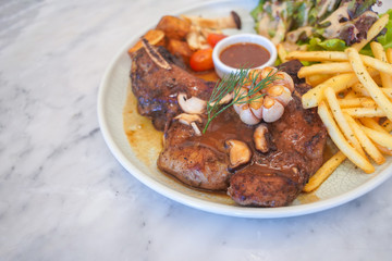 T-Bone steak with fresh vegetable salad and French fries.