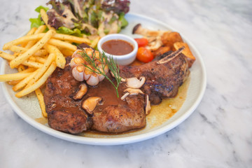 T-Bone steak with fresh vegetable salad and French fries.