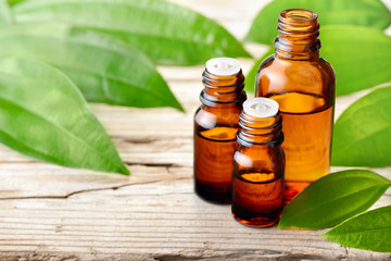 cinnamon leaf essential oil and fresh cinnamon leaves on the wooden board