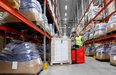 logistic business, shipment and loading concept - loader operating forklift with cargo at warehouse