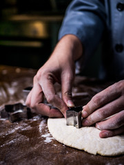 pastry chef hand use cutting mold to cut Cookie dough on kitchen table.