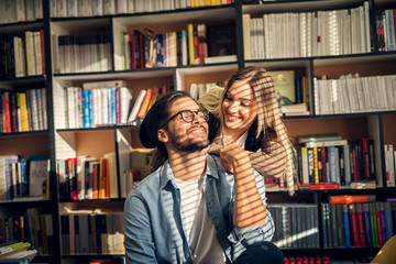 Happy beautiful smiling hipster couple studying together in library.