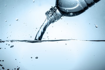 Water Pouring out of Plastic Bottle on the Light Blue Background - obrazy, fototapety, plakaty