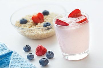 Healthy breakfast with yogurt strawberries and porridge with blueberries in a light key