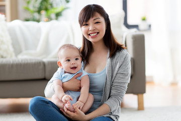 Fototapeta na wymiar family and motherhood concept - happy smiling young asian mother with little baby at home