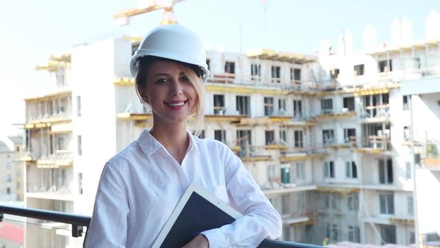 footage of a young engineer woman with helmet and tablet on building.