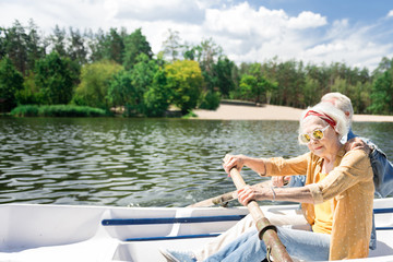 Woman rowing. Calm concentrated senior woman sitting in the boat near her husband and rowing