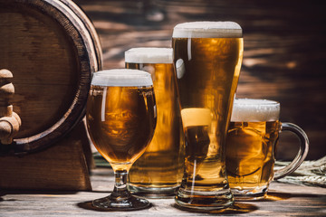 golden beer in glasses and beer barrel on wooden table, oktoberfest concept