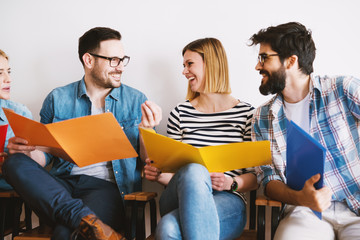 Group of young people sitting in a waiting room and talking.