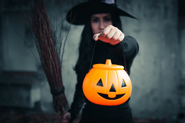 The witch in hand has Halloween pumpkin on dark background, Halloween day concept