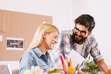 Happy young couple working together in the same office.
