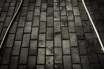 Hoses on sidewalk. Pavement tiles. Hosepipes. Abstract. Black and white photo. Grunge background