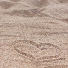 Fototapeta na wymiar Square photo of a sandy beach with a drawn heart