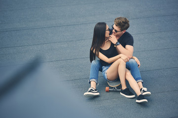 Fototapeta na wymiar beautiful multiethnic couple hugging and sitting on skateboard