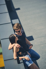 hot multicultural couple hugging on roof with beer bottle and cigarette pack near