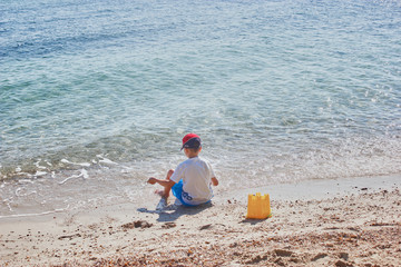 Fototapeta na wymiar Boy at the Beach plaing with sand