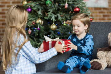 Fototapeta na wymiar adorable children in pajamas holding christmas gift at home