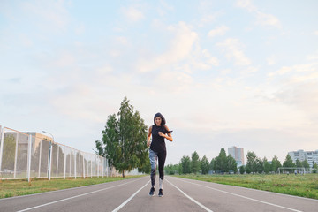 fit girl in hood running at the stadium outdoor