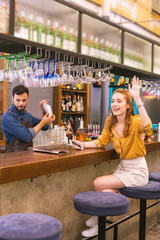 Hello. Cheerful emotional young girl sitting comfortably at the bar counter and feeling excited while waving to friends