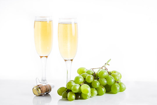 Champagne glasses and green grapes on white background