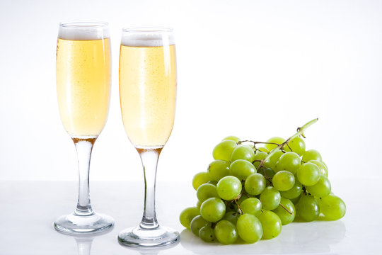 Champagne glasses and green grapes on white background