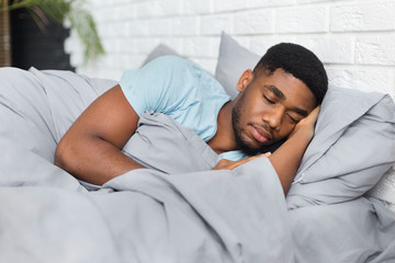Young african-american man sleeping in bed at home