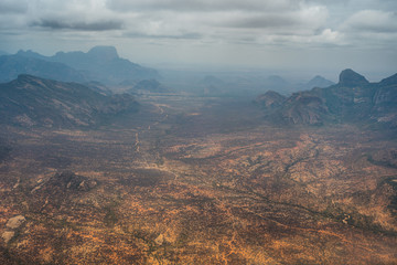 An aerial view of arid desert lands and jagged mountains on the edge of the sparsely-inhabited Kaisut desert in Northern Kenya