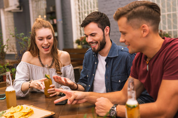 Counting. Positive young friends feeling interested and having fun while playing games in the bar