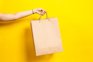 Girl carry a shopping bag close up on the yellow background.