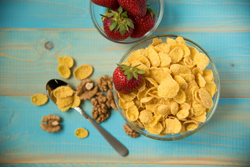 Tasty cornflakes with walnut and strawberries in glass bowl
