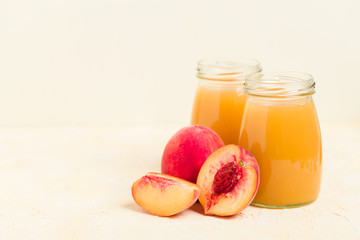 Peach smoothie in glass jars with fresh ripe fruits on yellow pastel background.