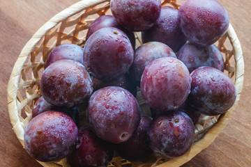 Fresh ripe plums in a basket close-up, organic healthy fruits