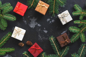 Multi-colored gift boxes and spruce branches on a dark background. Christmas background, top view. Flat lay,copy space