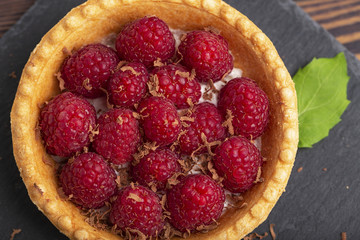Tartlet with cream and fresh raspberries, served on a slate plate.  Top view.