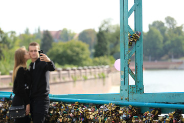 Piękna para młodych ludzi robi selfi na moście zakochanych we Wrocławiu.