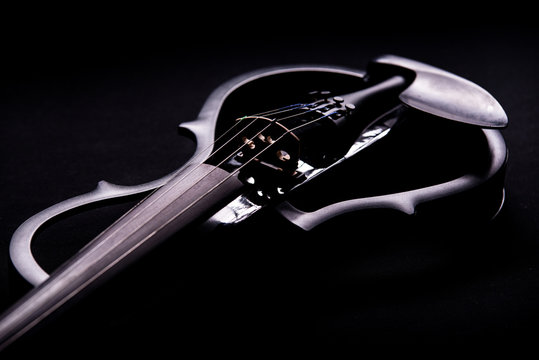 Beautiful black electric violin lying  on a black background