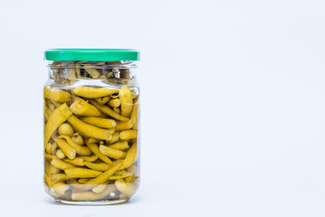 Pickled green chili pepper in a glass jar isolated on white background