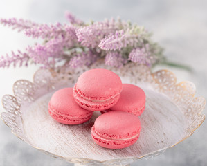Pink macaroons on a vintage plate and flowers. Pastel colored.