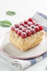 Napoleon cake with raspberries on a white table