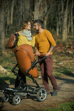 Family trust concept. Mother and father with baby pram enjoy sunny day in park, family trust. Road to life