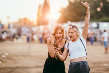 Young female friends having fun and using mobile phone