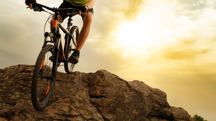 Cyclist Riding the Mountain Bike Down the Rock at Sunset. Extreme Sport and Enduro Biking Concept.