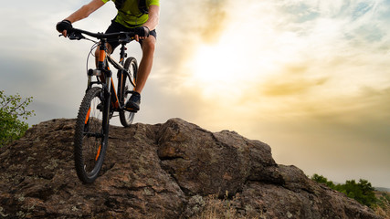 Naklejka na ściany i meble Cyclist Riding the Mountain Bike Down the Rock at Sunset. Extreme Sport and Enduro Biking Concept.