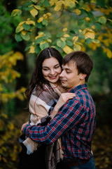 Close-up of man with woman laughing and hugging in forest in autumn