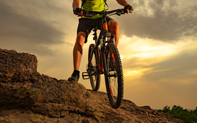 Fototapeta na wymiar Enduro Cyclist Riding the Mountain Bike on Rocky Trail at Sunset. Close-up of Bicycle. Active Lifestyle Concept.
