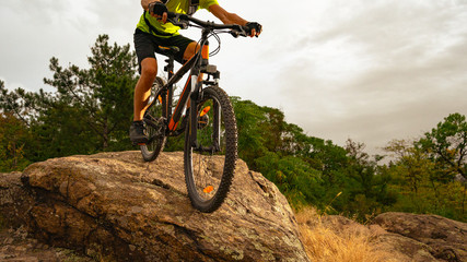 Obraz na płótnie Canvas Cyclist Riding the Mountain Bike Down the Rock at Sunset. Extreme Sport and Enduro Biking Concept.