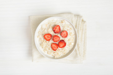 Oatmeal porridge with strawberry slices in bowl