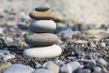 Fototapeta na wymiar Stones pyramid on sand symbolizing zen, harmony, balance.
