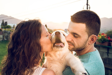 Couple with their puppy dog at sunset. Breed golden retriever